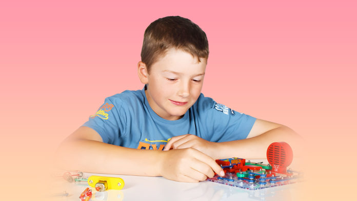 Young male student plays with electronic circuit toy