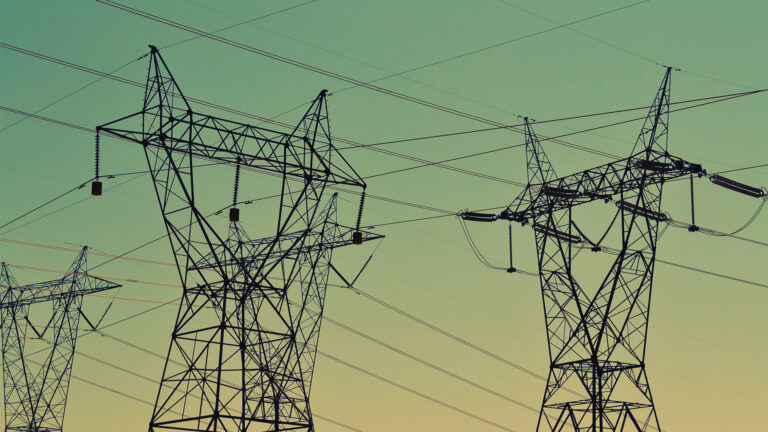 High-voltage transmission towers and power lines stretching across the sky at dusk, referencing the growing electricity demands driven by modern AI data centres.